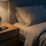 Comment savoir si dormir avec son téléphone est dangereux pour le sommeil ? Chambre calme au crépuscule avec un téléphone posé loin du lit sur une commode, un réveil analogique et une lumière douce.